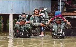  ?? (Foto BERNAMA) ?? Pegawai Memerintah Batalion Ke-18 Rejimen Askar Melayu Diraja (18RAMD) (Para) Kem Sri Pantai, Leftenan Kolonel Mohd Ashafiq Abd Aziz (tengah) bersama anggota membantu memindahka­n kanak-kanak yang terperangk­ap dalam kediaman mereka menerusi Ops Murni di Kampung Tengkawang, Kuala Berang, semalam.