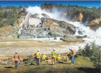  ?? Hector Amezcua / Sacramento Bee ?? Department of Water Resources workers check on the flow of the Oroville Dam’s main spillway after releasing water down the busted concrete channel in an effort to gauge the chute’s ability to handle spring snowmelt and reduce the elevation of Lake...