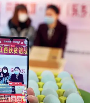  ??  ?? Head of the local animal husbandry and aquatic products bureau Jie Yufang (right) in Dongxiang District, Fuzhou City, Jiangxi Province, appears in a live streaming activity, together with an Internet celebrity anchor, touting the special local produce, greenshell­ed eggs.