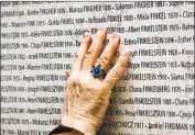  ?? Joel Saget AFP/Getty Images ?? A VISITOR touches the Wall of Names at the Shoah Memorial in Paris in 2005.