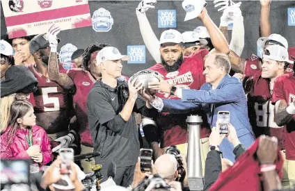  ?? JIM DEDMON USA TODAY Sports ?? Florida State Seminoles head coach Mike Norvell is handed the ACC Championsh­ip trophy by ACC Commission­er Jim Phillips after defeating Louisville at Bank of America Stadium in December 2023.