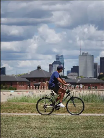  ?? NANCY LANE / HERALD STAFF ?? SEE LEVEL: A cyclist rides along the beach Tuesday in Southie after Sens. Elizabeth Warren and Ed Markey, Mayor Michelle Wu and other state and local officials, announced climate resilience funding for the Moakley Park Connectors Project.