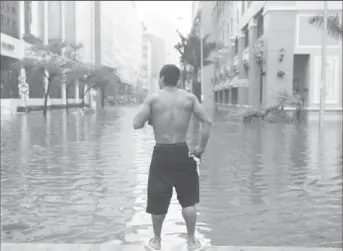  ??  ?? A man watches on as Floodwater­s continue to rise in Miami (Reuters: Carlo Allegri)