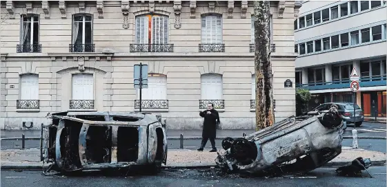  ?? THIBAULT CAMUS
THE ASSOCIATED PRESS ?? A man takes a snapshot of charred cars near the Arc de Triomphe on Sunday, the day after a protest against rising taxes and the high cost of living turned into a riot in the French capital.