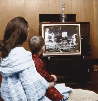  ??  ?? 1969 Dans la nuit du 20 juillet, une maman et son fils assistent aux premiers pas de l’homme sur la Lune. Ce moment magique marquera les esprits des nombreux enfants présents devant le poste.