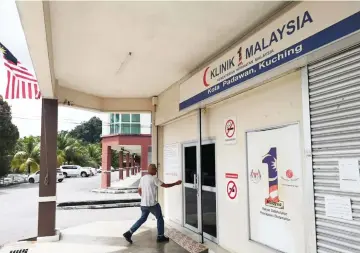  ??  ?? A cleaning service contractor walks into the 1Malaysia Clinic at Kota Padawan after it was reopened today.