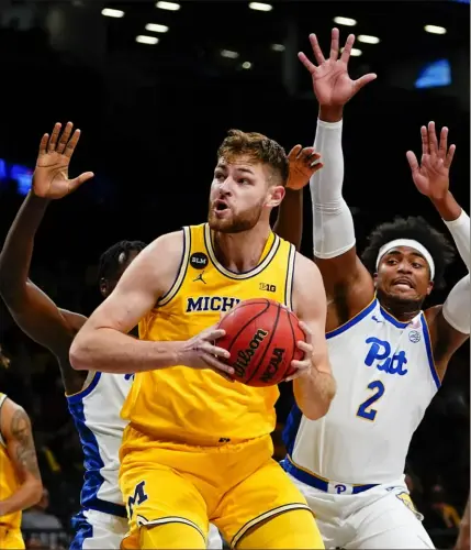  ?? Frank Franklin II/Associated Press ?? Michigan’s Hunter Dickinson, center, looks for an opening Wednesday night against PItt’s Blake Hinson, right, and another Panthers defender in the Legends Classic at Barclays Center in New York.
