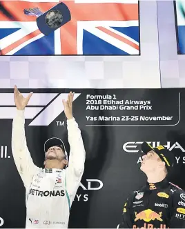  ?? Picture: AFP ?? SAFE HANDS. World champion Lewis Hamilton throws his winner’s trophy up in the air as third-placed Max Verstappen looks on after the Abu Dhabi F1 Grand Prix at the Yas Marina circuit yesterday.