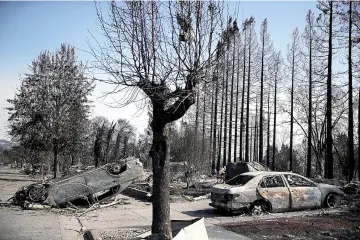  ??  ?? An overturned car sits in front of homes that were destroyed by the Tubbs Fire in Santa Rosa, California. — AFP photo