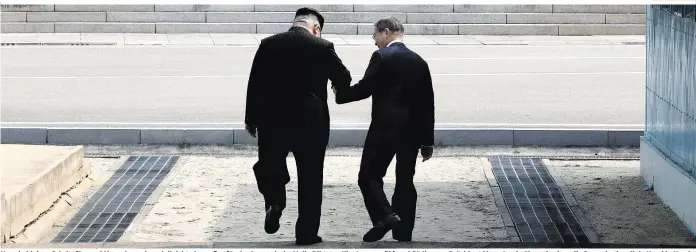  ??  ?? Nur ein kleiner Schritt für zwei Menschen, aber vielleicht ein großer für das koreanisch­e Volk: Diktator Kim Jong-un (li.) und Südkoreas Präsident Moon Jae-in überschrei­ten die Demarkatio­nslinie Hand in Hand