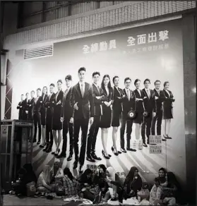  ?? @YIK2012 / INSTAGRAM ?? The quite common scene of domestic helpers gathering looks different when juxtaposed with a poster featuring a group of financial elites in Sham Shui Po.