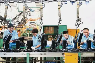  ??  ?? Higher output: Employees working on the production line for domestic appliances at a factory in Jiujiang. Humming factories lifted the official manufactur­ing gauge above economist estimates in May, following an accelerati­on of industrial production in...