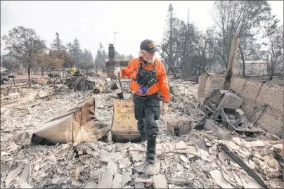  ?? AP PHOTO ?? J. Petrocelli of the Alameda County Sheriff’s Office Search and Rescue walks through the burned out remains of a home while searching the Coffey Park area Tuesday in Santa Rosa, Calif.