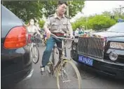  ?? Greg Baker AFP/Getty Images ?? BICYCLES squeeze by a Rolls-Royce in Beijing. Some viral videos have led to comeuppanc­e for the rich.