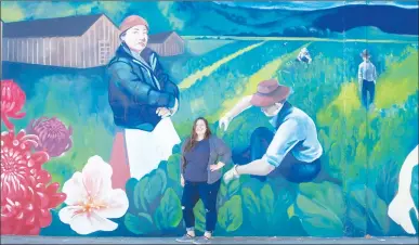  ?? Courtesy photo ?? Local muralist Madelyne Templeton stands in front of her newly completed work, “History of the Japanese Americans,” located in the parking lot of the Marysville Buddhist Church.