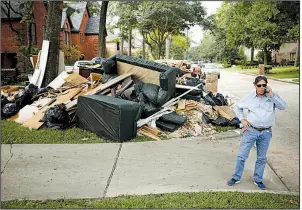  ?? Bloomberg file photo ?? Constructi­on company owner Frank Jones talks on a cellphone next to debris from a house in Spring, Texas, that was flooded after Hurricane Harvey in September 2017. A bill to overhaul the Federal Emergency Management Agency’s flood insurance program has been stalled in Congress since November.
