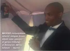  ??  ?? MASEKO menunjukka­n sebotol minyak hitam dalam satu upacara di gereja miliknya di Daveyton, Afrika Selatan. - Agensi