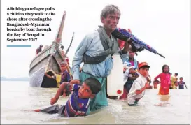  ??  ?? A Rohingya refugee pulls a child as they walk to the shore after crossing the Bangladesh-myanmar border by boat through the Bay of Bengal in September 2017