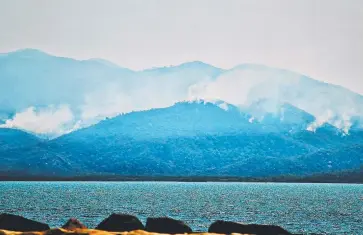  ??  ?? TIMELY PRECAUTION: Smoke rises from Magnetic Island as backburnin­g operations are carried out.