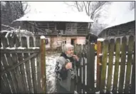  ?? (AP/Andreea Alexandru) ?? An elderly woman adjusts her mask while watching Nicolae deliver basic goods to families with school children.