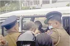  ?? — AFP ?? Police officers escort into a vehicle Tamil legislator Selvarajah Kajendran.