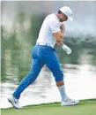  ??  ?? Jason Day plays a shot with a leg in the water on the 14th.