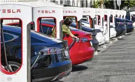  ?? GRITCHEN / THE ORANGE COUNTY REGISTER ?? Drivers charge their Teslas in Santa Ana, Calif., last month. After reporting dismal first-quarter sales, Tesla is planning to lay off about a tenth of its workforce as it tries to cut costs. JEFF