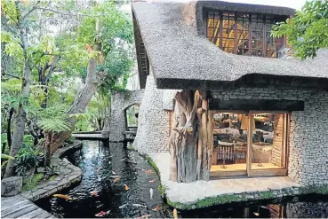  ??  ?? An aerial view of Keith Rose’s Cape Town home, Blackwood Lodge, which features an undergroun­d wine cellar separated by windows from a koi pond, left; right, the moat-like koi pond and the house with its sandstone exterior finish.