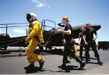  ?? © USAF ?? En route pour un tournage fétichiste? Pas vraiment… La technicien­ne porte la valise de conditionn­ement d’air qui ventile la combinaiso­n étanche du pilote.