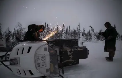  ??  ?? Anatolij och Aleksej Taiberi försöker reparera sin trasiga snöskoter. Den som bor på tundran måste förstå sig inte bara på naturen utan också på mekanik.