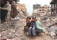  ?? AFP ?? A Palestinia­n family rides on ■ the back of a donkey-drawn carriage next to damaged buildings in Khan Younis yesterday.