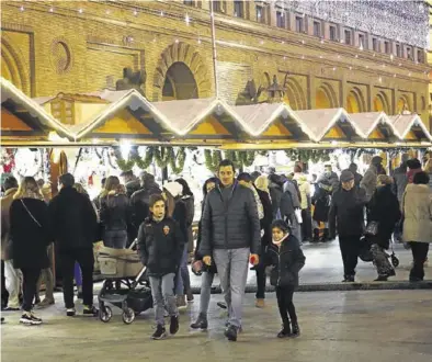  ?? JAIME GALINDO ?? Varias personas pasean por los puestos del mercado de Navidad, ayer.