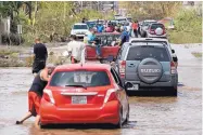  ?? CARLOS GIUSTI/ASSOCIATED PRESS ?? Residents attempt to drive through a flooded road after the passing of Hurricane Maria in Toa Baja, Puerto Rico, Friday. Thousands were evacuated from the area.