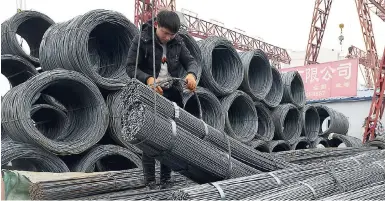  ?? AP ?? A worker loads steel products on to a vehicle at a steel market in Fuyang in central China’s Anhui province on March 2.