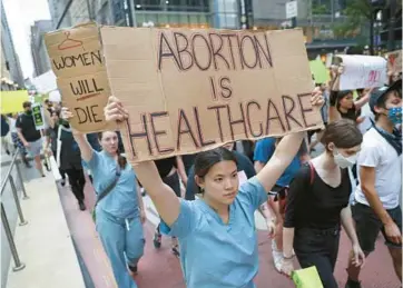  ?? CHRIS SWEDA/CHICAGO TRIBUNE ?? People march in protest through downtown Chicago on Saturday a day after the Supreme Court overturnin­g Roe v. Wade, allowing states to ban abortions.