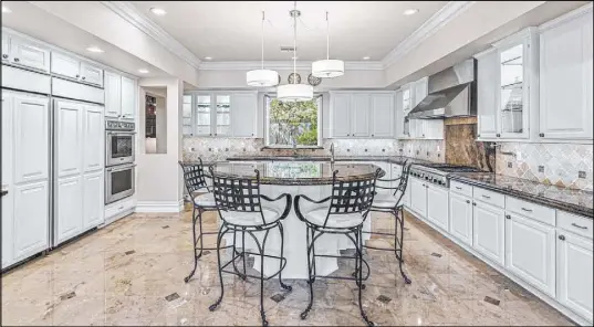  ??  ?? The large chef ’s kitchen has an oversized tiered island that offers bar seating. It also features Verde Fire marble countertop­s, new profession­al-grade appliances, custom cabinetry and a butler’s pantry.