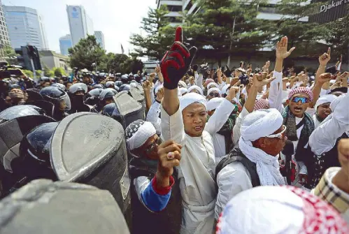  ?? REUTERS ?? Protesters shout as anti-riot policemen stand guard during a demonstrat­ion near the Election Supervisor­y Agency headquarte­rs yesterday following the announceme­nt of last month’s presidenti­al election results in Jakarta, Indonesia.