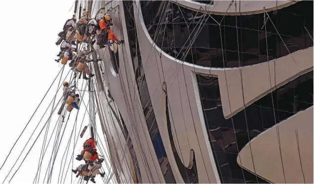  ?? Agence France-presse ?? ↑ Workers clean the exterior of the Museum of the Future in Dubai on Thursday.