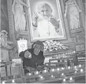  ?? Getty Images ?? A nun lights a candle at the Vatican the day before the canonizati­on of Pope John Paul II in April 2014.