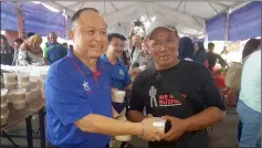  ??  ?? Chan (left) presents a container of ‘bubuk lambuk’ to a member of the public at Stutong Community Market Ramadan Bazaar.