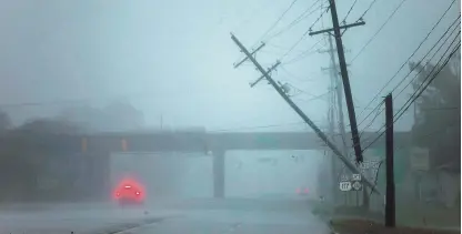  ?? EFE ?? Menos fuerza, más agua. Postes de la luz semi caídos tras el paso del huracán Florence, en Wilmington. Florence, que tocó ayer tierra en Carolina del Norte continúa perdiendo fuerza, pero avanza lentamente dejando inundacion­es en partes de las Carolinas.