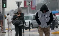  ?? Photo By Ryan Lim ?? Drenched in rain but that did not deter these residents from taking a stroll in Abu Dhabi on Sunday. —