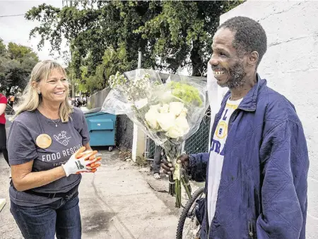  ?? PEDRO PORTAL pportal@miamiheral­d.com ?? Ellen Bowen, founder of the South Florida chapter of Food Rescue US, chats with Antwan
Griffin, who picked up a tote bag full of food and a bouquet of flowers at the pantry.