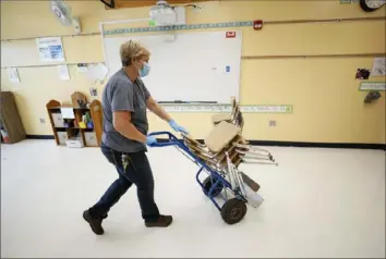  ?? Charlie Neibergall/Associated Press ?? Des Moines Public Schools custodian Cynthia Adams moves a stack of chairs out of a classroom Wednesday at Brubaker Elementary School in Des Moines, Iowa.