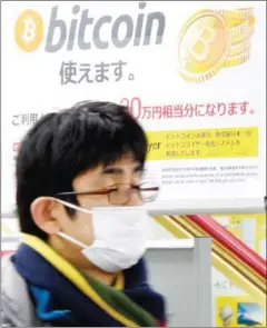  ?? TORU YAMANAKA/AFP ?? A man walks past a poster that informs customers that bitcoin can be used at a shop in Tokyo on Saturday.