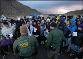  ?? GREGORY BULL / ASSOCIATED PRESS ?? U.S. Border Patrol agents, front, speak with migrants seeking asylum, mainly from Colombia, China and Ecuador, in a makeshift, mountainou­s campsite after crossing the border between Mexico and the United States on Friday near Jacumba, Calif.