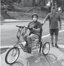  ?? CONTRIBUTE­D ?? Jarod Boddy uses one of the County of Antigonish’s adapted tricycles. He’s supported by Jeff Teasdale. The county and town’s equipment loan program has a variety of outdoor equipment to choose from.