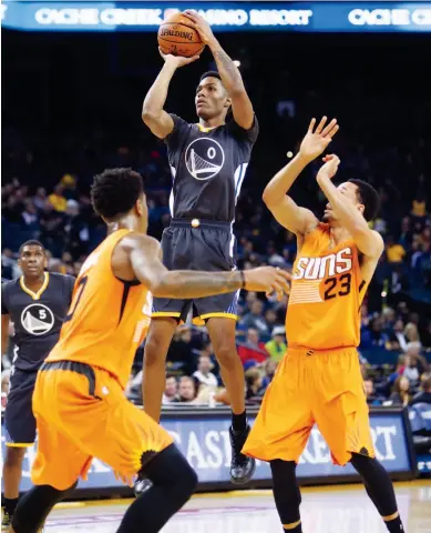  ??  ?? Andre Iguodala makes the internatio­nal sign for a three-pointer at left. Above, Warriors rookie guard Patrick McCaw shoots between the Phoenix Suns’ Marquese Chriss and John Jenkins (23).