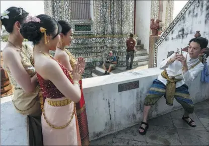  ?? BLOOMBERG / GETTY IMAGES ?? Chinese tourists in traditiona­l Thai dress pose for a photograph at the Wat Arun Buddhist temple in Bangkok, Thailand, on Jan 24.