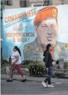 ?? ?? Caracas. Personas ladean un mural del fallecido Hugo Chávez.